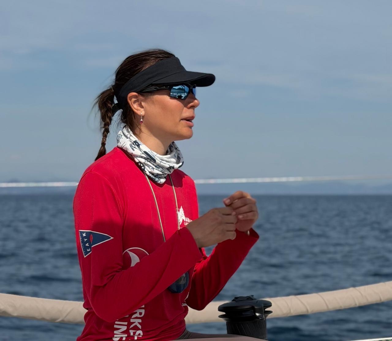 Belemir Dedeoğlu on the boat during the race, watching the wind in a red sailing jersey and hat