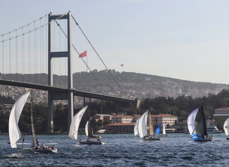 Boğaz Köprüsü altında yelken sponsorluğu logoları taşıyan yarış tekneleri