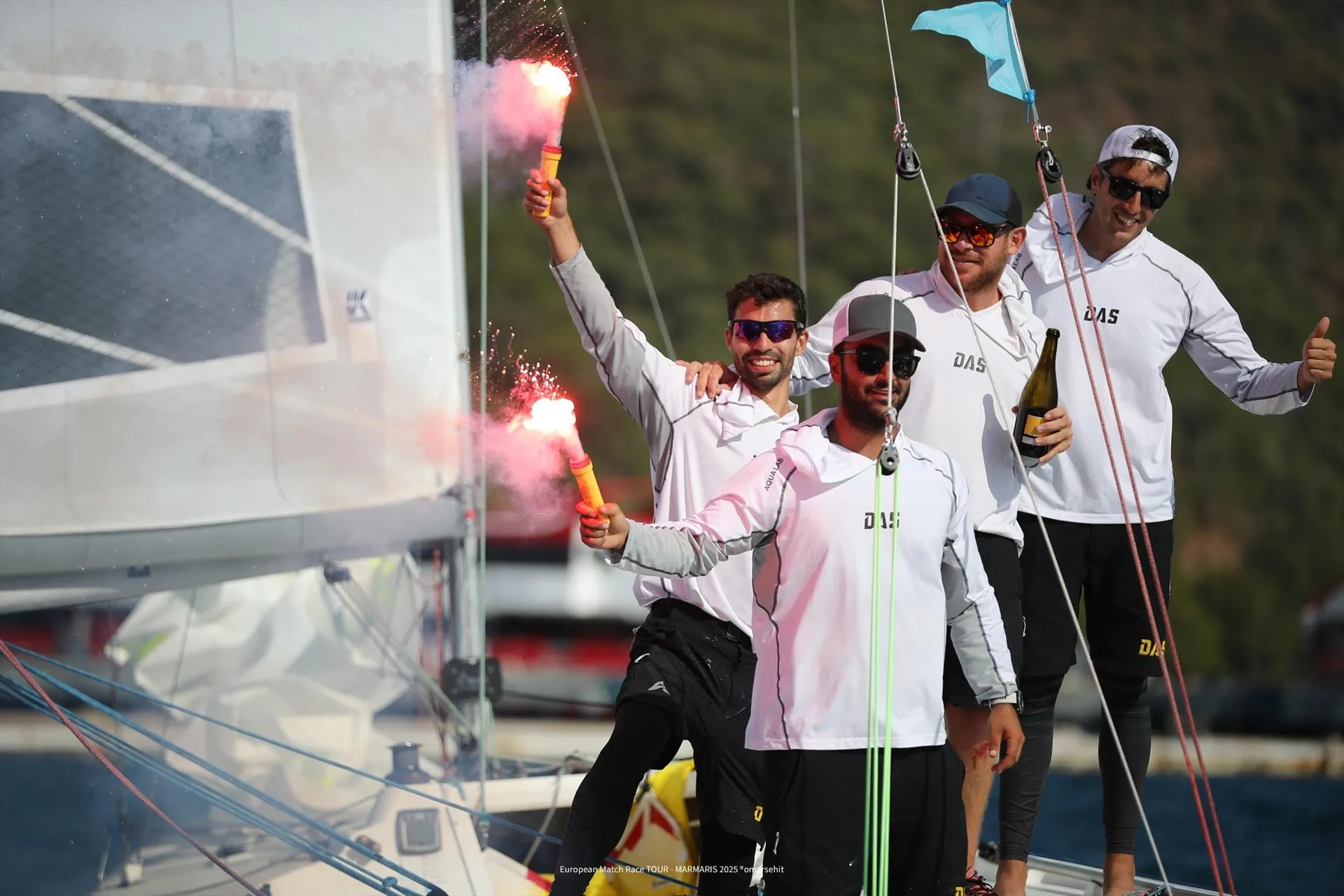 Doğa Arıbaş Sailing team celebrating with hand flares on the deck of an 11MOD at the European Match Race Tour Marmaris 2025